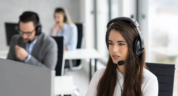 Close up portrait of female call-center agent with headset working in hotline at office