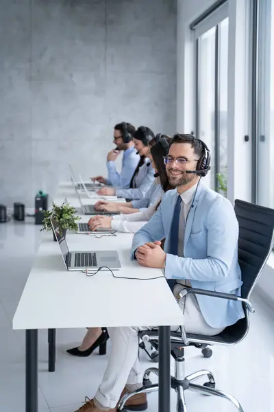 Call center agent engaging in a conversation with a client, with a headset on, agent attentively listens to the clients needs while surrounded by supportive colleagues
