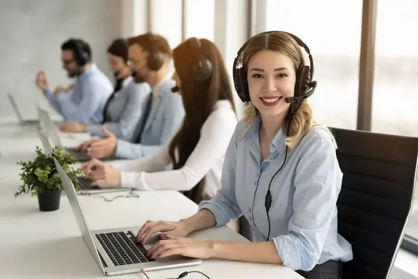 Przyjazna Telefonistka Słuchawkami Rozmawiająca Klientem Wykazująca Się Doskonałymi Umiejętnościami Komunikacyjnymi — Zdjęcie stockowe