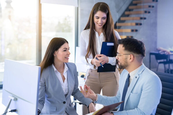 Group of business people discussing business related topics and making decisions as a team in a meeting around computer desk at office.