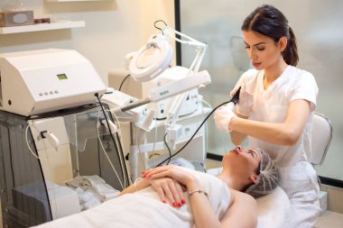 Ultrasonik süzgeci olan doktor güzellik salonunda kadın müşterinin boynunu ultrasonik olarak temizliyor..