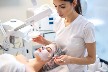 Yüzü soyan güzellik uzmanı maske, kaplıca güzellik tedavisi, cilt bakımı. Güzellik salonundaki kadın yüz bakımı yaptırıyor, yakın plan..