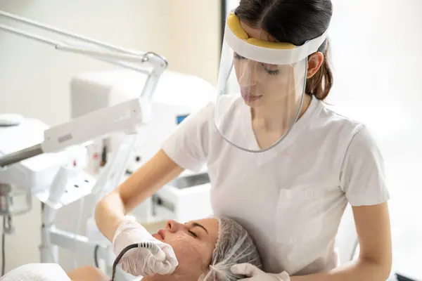 Kosmetikerin Mit Gesichtsschutz Führt Kosmetologische Eingriffe Mit Radiofrequenz Schönheitsmaschine Zur — Stockfoto