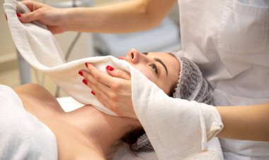 Güzel genç bir kadın güzellik salonunda yüz bakımı yaptırıyor.