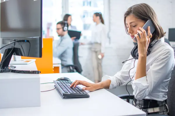 携帯電話で話し 悪いニュースを得て オフィスでコンピュータで作業中に落ち込んでいるビジネスウェアに懸念する女性 — ストック写真