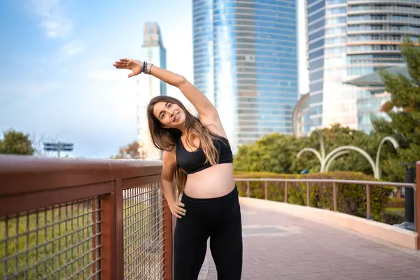 市立公園の屋外に伸びるスポーツウェアの美しいスポーティーな妊婦 — ストック写真