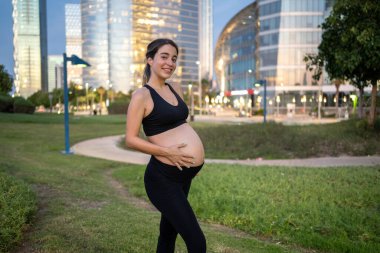 Eğitiminden sonra parkta duran hamile bir kadın.