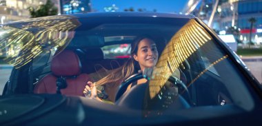 Geceleri araba süren neşeli genç bir kadın.