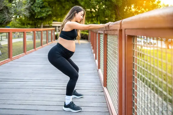 屋外のフェンスの上のスカートをするスポーティーな妊婦の完全な長さの側面の眺め 妊娠と健康的なライフスタイルの概念 — ストック写真
