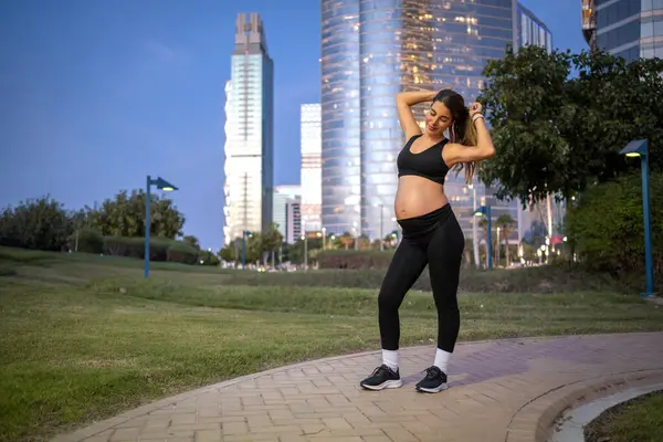 夜に公園でポーズするスポーツウェアで美しい若い妊婦 — ストック写真