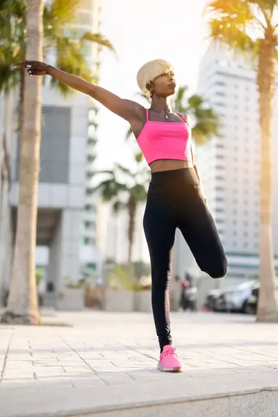 スポーツウェアの美しい黒人女性は 彼女の筋肉を伸ばし 街路で走る前に暖かくなります — ストック写真