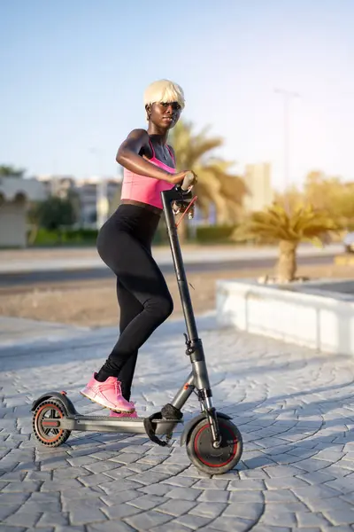 街上有一个年轻的有运动能力的黑人妇女 她有一辆电动车 — 图库照片