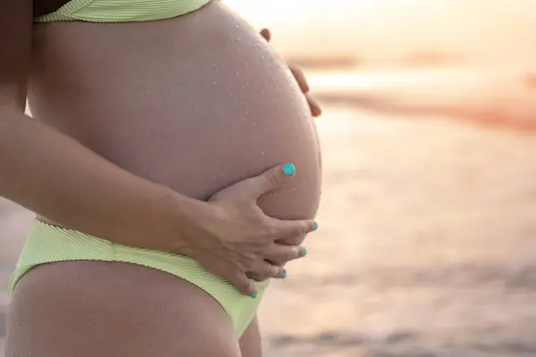 Zblízka Těhotné Ženy Břicho Nosí Žluté Bikiny Pláži Při Západu — Stock fotografie