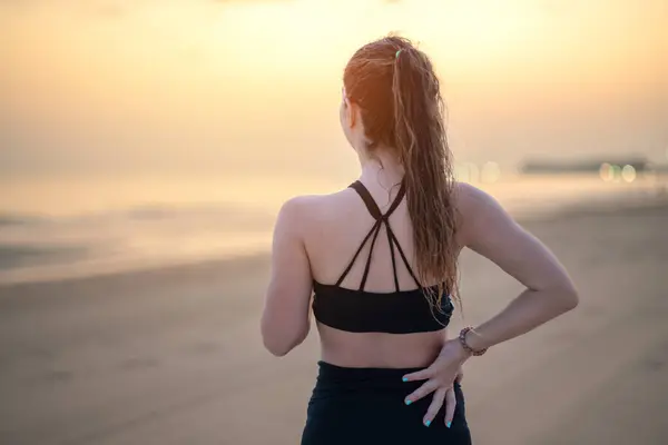 Spor Kıyafetli Atletik Bir Kadın Deniz Kenarında Durmuş Sırtını Ovuşturuyor — Stok fotoğraf