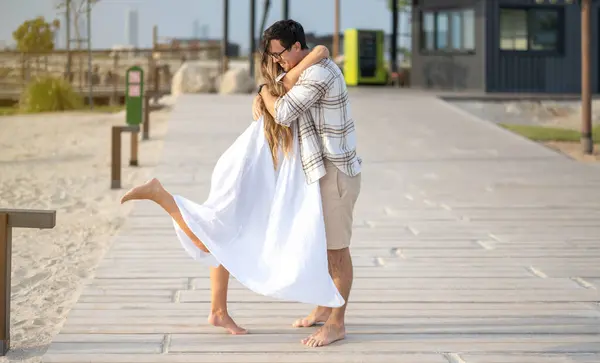 ハッピー若いカップルは ビーチの歩道に立っている間抱擁し — ストック写真