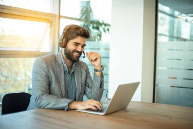 Ofisteki müşteriyle konuşurken kulaklık kullanan çok ırklı bir iş adamı.