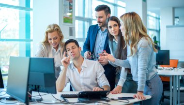 Şirket performansını geliştirmek için bilgisayar masasının etrafında toplanan bir grup kendinden emin iş adamı fikir paylaşıyor ve iş hedefleri belirliyor..