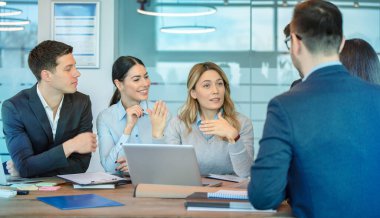 Bir grup şirket çalışanı, modern ofiste orta yaşlı başarılı bir kadın liderle toplantı yapıyor. Personel toplantısı ve kadın lider konsepti..