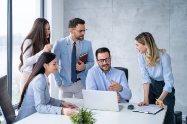 İş ekibi proje tartışıyor ve ofis masası etrafında bir toplantıda iletişim kuruyor.