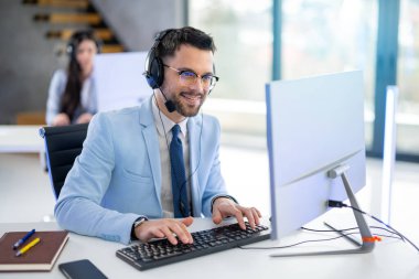 Ofiste bilgisayarla çalışan gülümseyen yakışıklı adam.