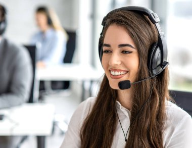 Arama merkezindeki soruları araştırarak ve cevaplayarak kullanıcılara teknik destek sağlayan kulaklıklı kadın yardım masası çalışanı.