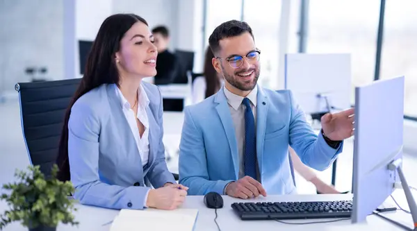笑顔のビジネスマンと女性がテーブルに座り オフィスでコンピュータ上でプロジェクトを議論する — ストック写真
