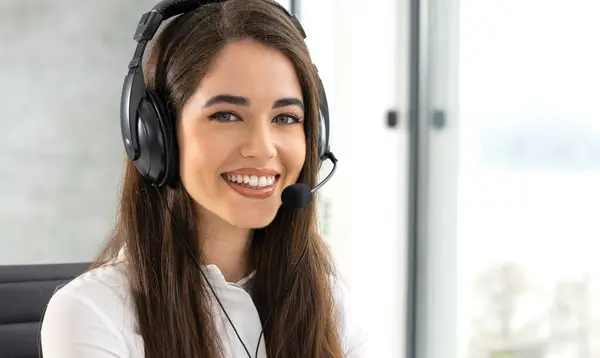 Close up portrait of smiling female customer service consultant with headset talking with client during phone call