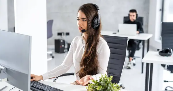 Young operator woman having online voice chat in call center office