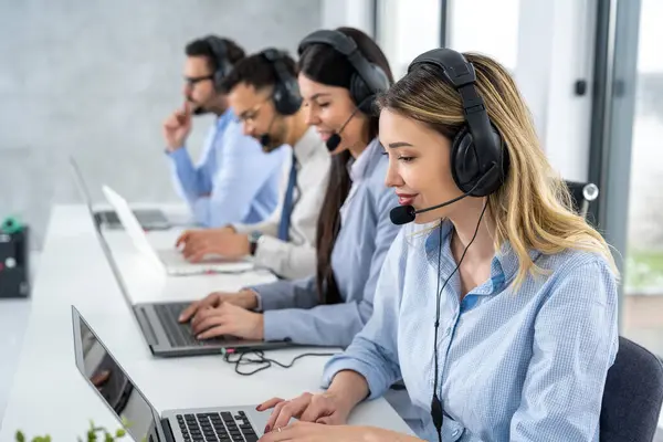 Çağrı merkezinde bir grup iş arkadaşıyla birlikte çalışan çekici sarı saçlı genç bir kadın.