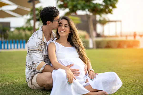 Beautiful Pregnant Woman Sitting Her Husbands Arms Grass Park Handsome — Stock Photo, Image