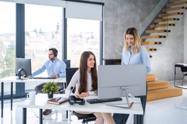 Güzel iş kadınları modern ofiste bilgisayar önünde toplantı yapıyorlar.