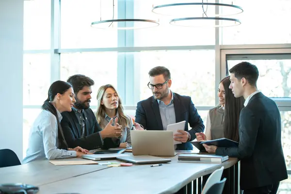 Ofisteki dizüstü bilgisayara bakıp yeni bir projeye başlamak için işbirliği yapan büyük bir iş adamı grubu.