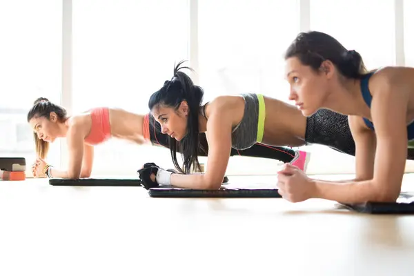 Drei Attraktive Sportlerinnen Bei Brettgymnastik Liegend Auf Yogamatte Fitnesskurs — Stockfoto