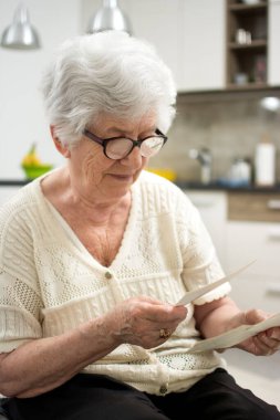 Büyükanne evde oturuyor ve eski fotoğraflara bakıyor..