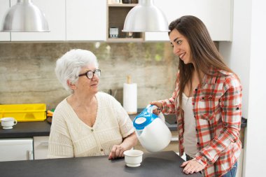 Genç torun büyükannesine sıcak içecek getiriyor..