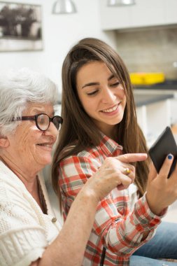 Büyükannesi cep telefonundan küçük torununa bir şey gösteriyor..