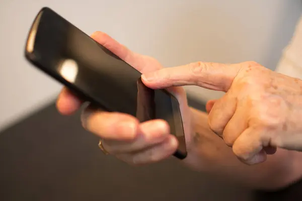 靠近一个接触智能手机的皱巴巴的手指 — 图库照片