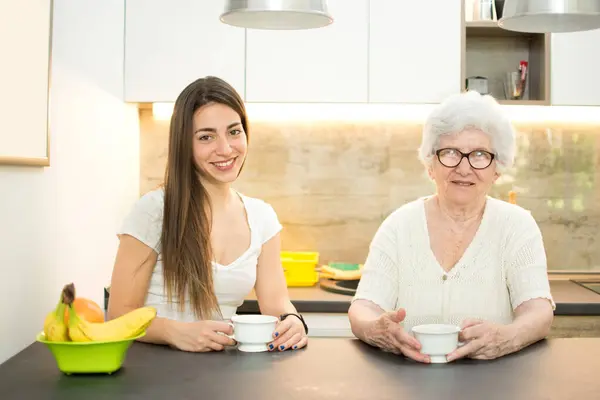 Neta Avó Sentados Cozinha Juntamente Com Xícaras Chá Olhando Para — Fotografia de Stock