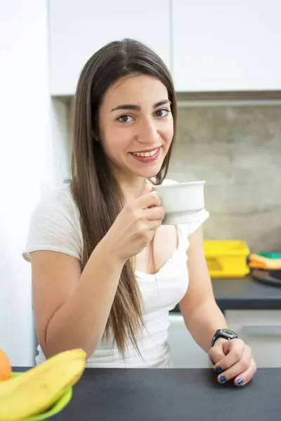 快乐微笑的年轻女人 在厨房里喝茶或喝咖啡 — 图库照片