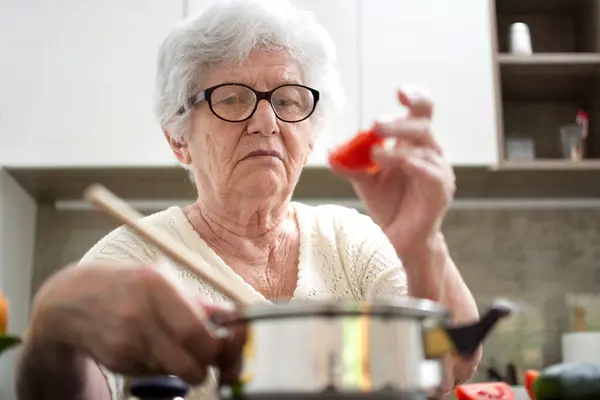 Kıdemli Kadın Sebzeli Yemek Hazırlıyor Yaşlı Kadın Tencereye Domates Koyuyor — Stok fotoğraf