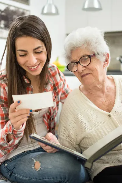 孙女和祖母坐在沙发上 看着旧照片做广告 图库图片