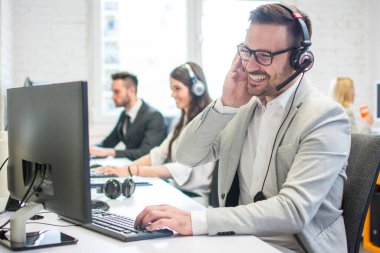 Gülümseyen çağrı merkezi çalışanı, müşterilere teknik destek veriyor..