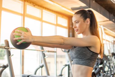 Güzel genç bayan spor salonunda spor topuyla egzersiz yapıyor..