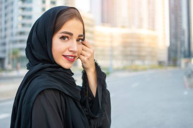 Geleneksel Arap kıyafetleri giymiş güzel bir Arap genç kadının portresi. Gülümseyen Arap kadın elinde peçeyle.