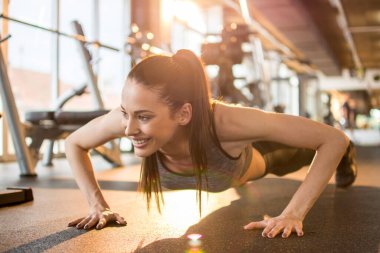 Spor salonunda şınav çeken genç bir kadın..