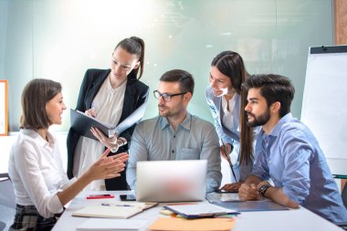 İş adamları toplantı masasında oturmuş iş ve planlama stratejilerini tartışıyorlar.