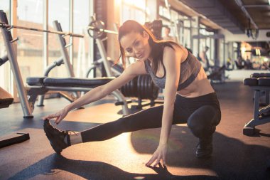 Spor salonunda antrenman yapmadan önce bacaklarını esneten formda bir kadın..