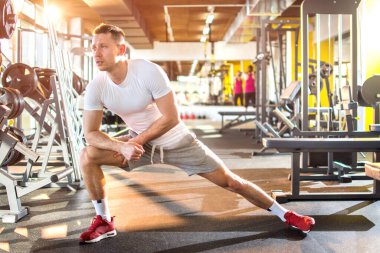 Genç sporcu ısınıyor ve spor salonunda esneme egzersizleri yapıyor.