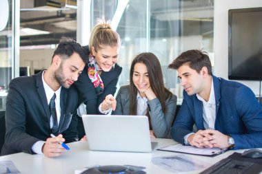 Modern ofiste bir dizüstü bilgisayar kullanarak birlikte çalışan iş ekibi.