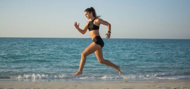 Kumsalda koşan sporcu kızın panoramik manzarası